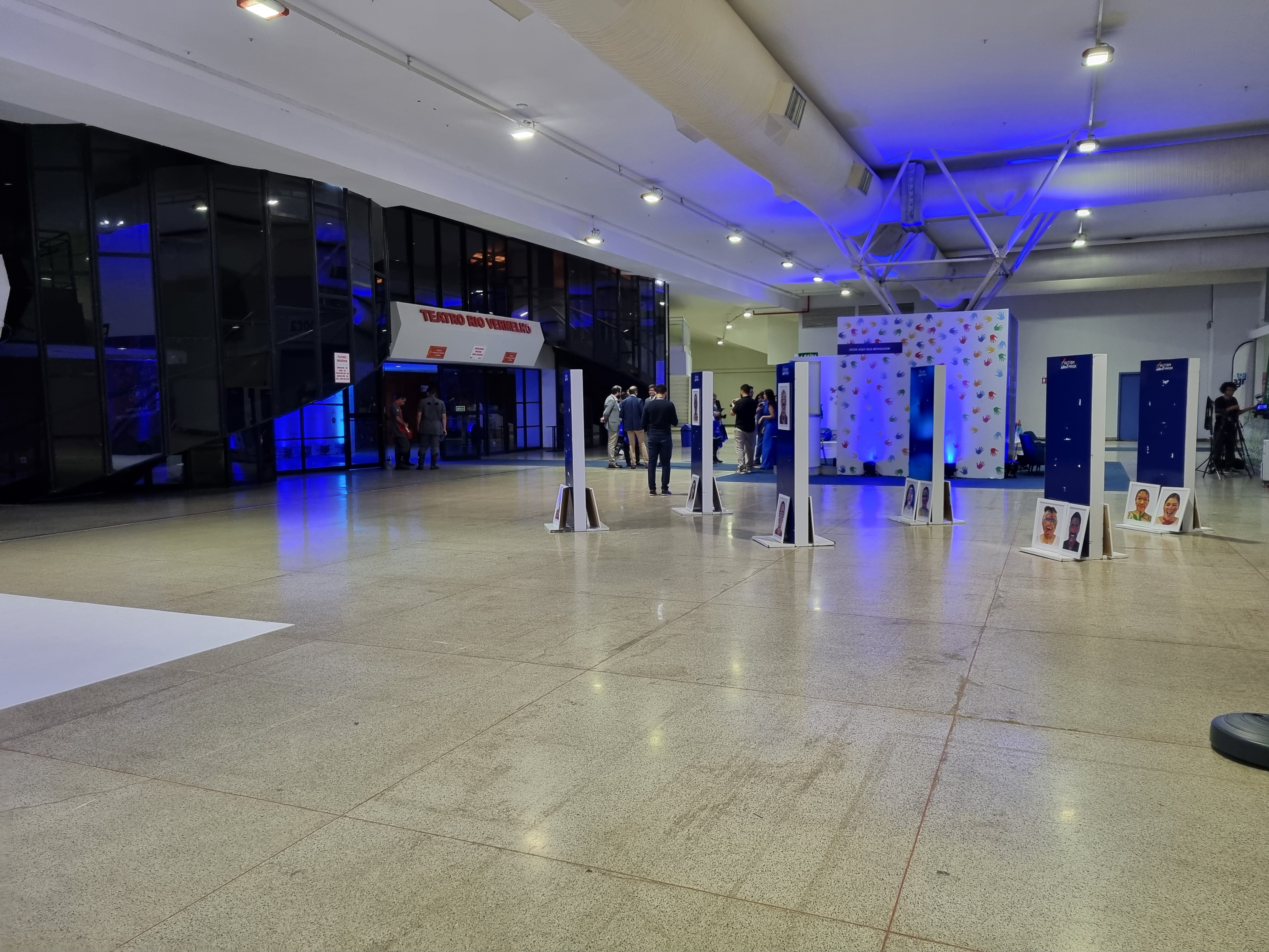 Área de recepção do Centro de Convenções de Goiânia durante um congresso, com totens e iluminação azul